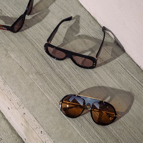 Sur les marches en béton sont posées deux paires de lunettes de soleil, l'une à monture noire et l'autre à monture dorée et noire, et le soleil se reflète dans leurs verres.