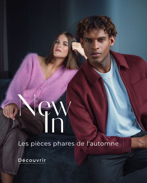 Deux mannequins sont assis sur un canapé et présentent la mode automne : une femme en pull rose, un homme en veste bordeaux. Le texte indique « Nouveautés » et « Les pièces phares de l'automne ».